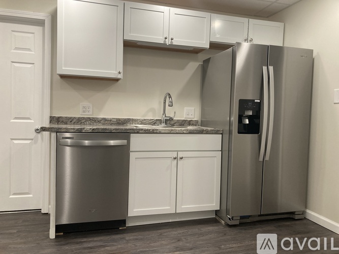 A kitchen with a stainless steel refrigerator and white cabinets.