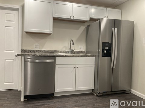 A kitchen with a stainless steel refrigerator and white cabinets.