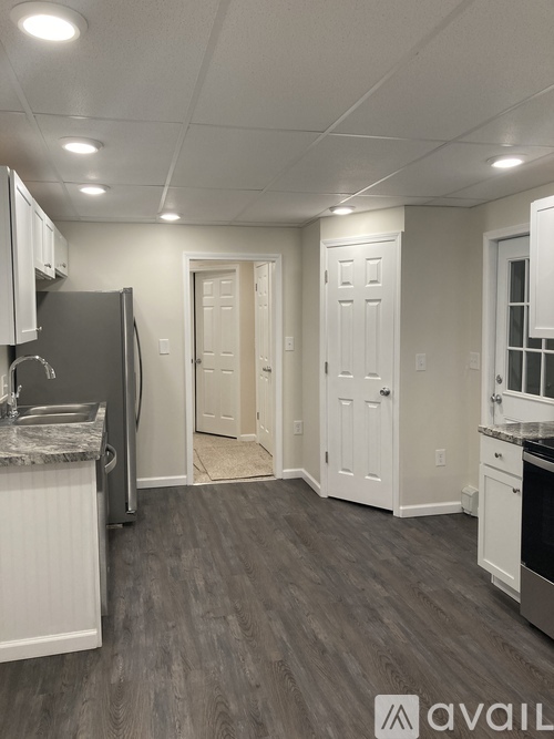A kitchen with a refrigerator, sink, and cabinets.