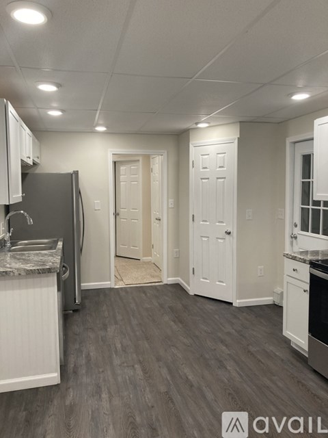 A kitchen with a refrigerator, sink, and cabinets.