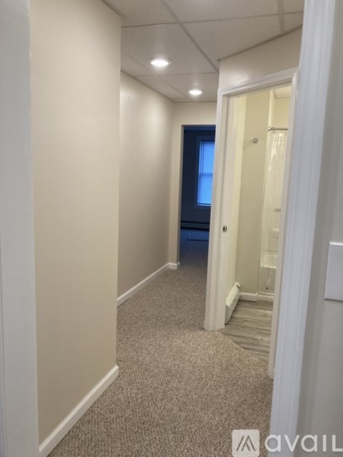 A hallway with a carpeted floor and white walls.
