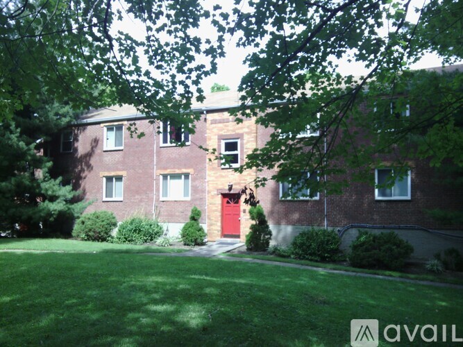 A brick building with a red door and a green lawn in front.