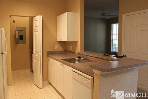 A kitchen with white cabinets and a refrigerator.