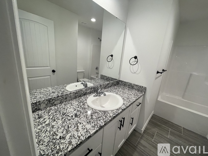 A bathroom with granite countertops and a white door.