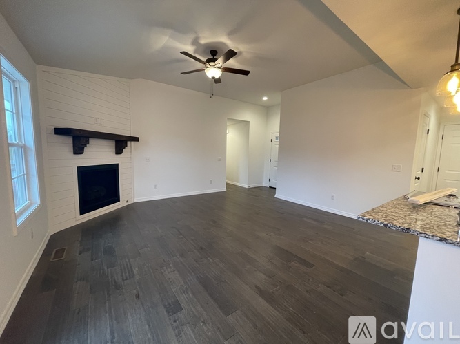 A spacious room with a fireplace and a ceiling fan.