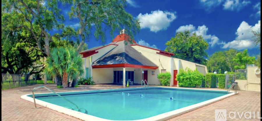 A pool in front of a house with a red roof.