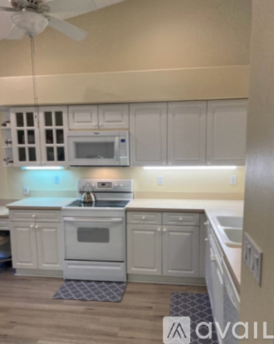 A kitchen with white cabinets and a white stove top oven.