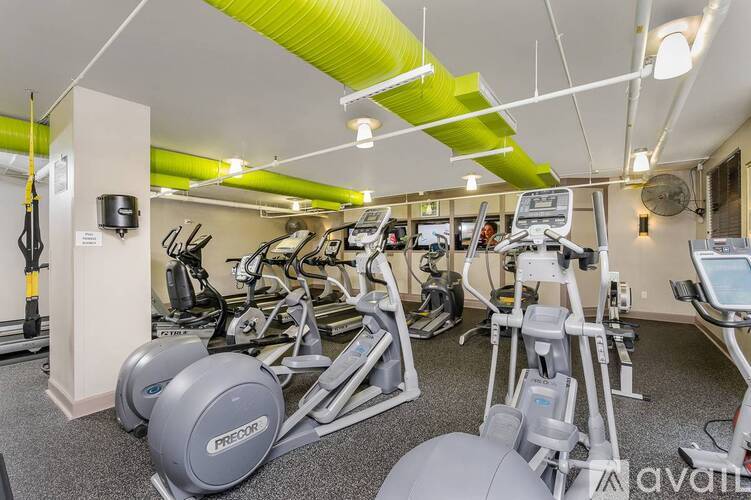 A gym with a variety of exercise equipment including treadmills, stationary bikes, and weight machines.