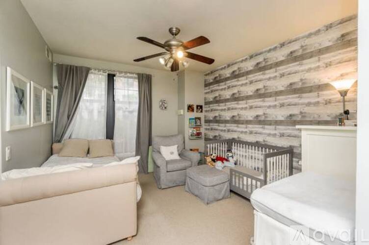A bedroom with a white bed and a grey ottoman.