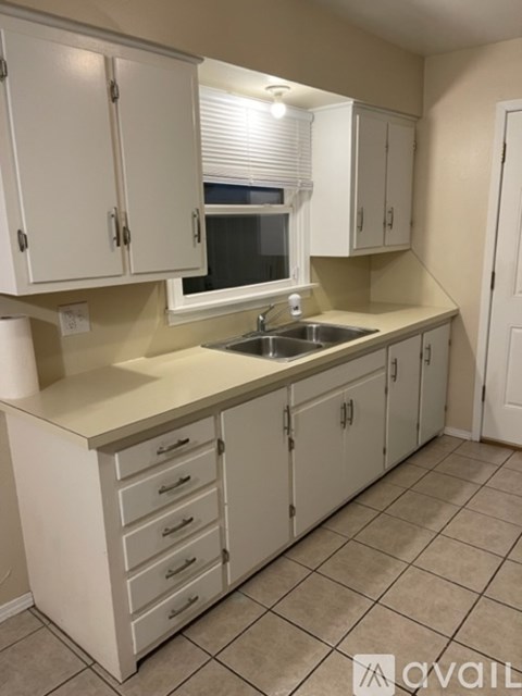 A kitchen with white cabinets and a sink.