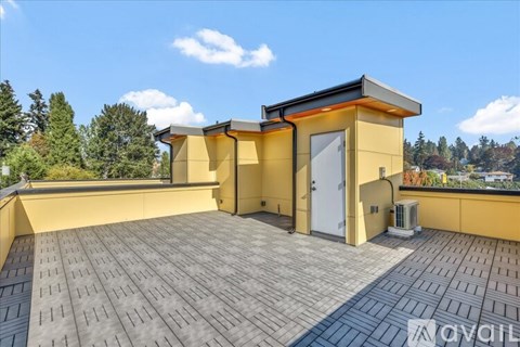 A yellow house with a black roof and a tiled roof terrace.