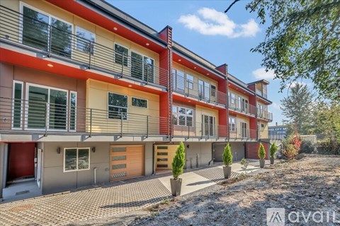 A row of modern townhouses with red and beige exteriors and balconies.