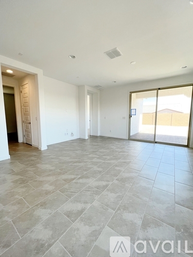 A spacious room with tiled flooring and a sliding glass door leading outside.
