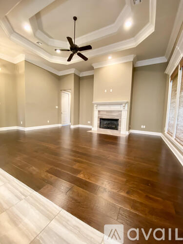 A spacious room with wood flooring and a ceiling fan.