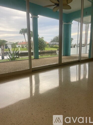 A room with a fan and a view of the outdoors through the glass doors.