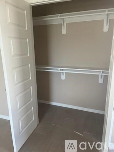 A white door is open to a room with grey walls and a grey floor.