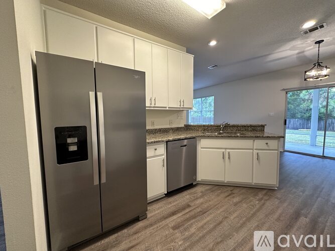 A kitchen with a stainless steel refrigerator and white cabinets.