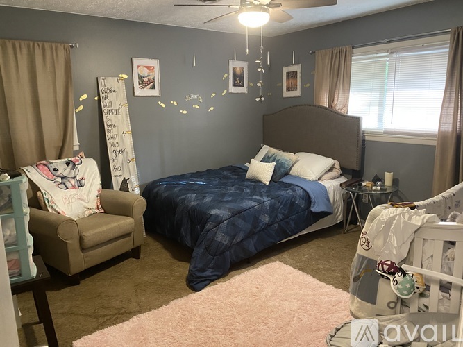 A bedroom with a bed, chair, and a fan.