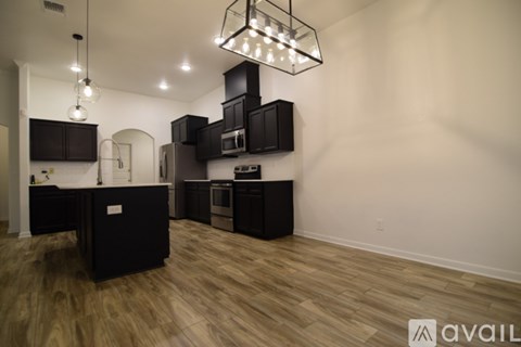 A kitchen with black cabinets and a wooden floor.