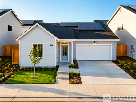 A white house with a black roof and solar panels on the roof.
