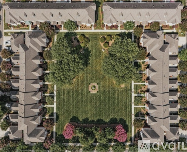 A bird's eye view of a neighborhood with houses and a central green space.