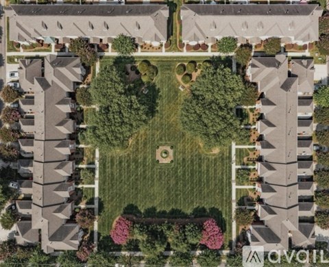 A bird's eye view of a neighborhood with houses and a central green space.