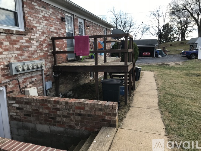 A brick house with a wooden deck and a trash can.