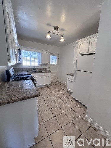 A kitchen with white cabinets and a brown countertop.