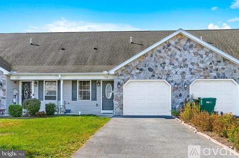 A house with a grey front and a stone wall.