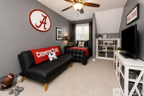 A living room with a black couch and a football on the floor.
