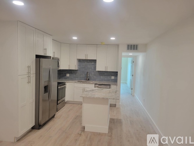 A kitchen with white cabinets and a stainless steel refrigerator.