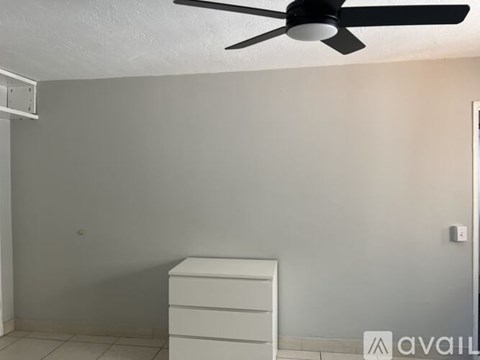 A room with a ceiling fan and a white cabinet.
