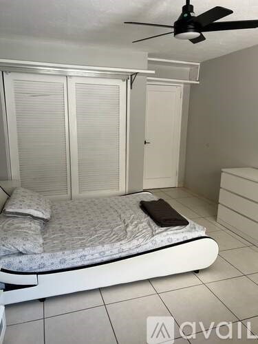 A bedroom with a bed, a ceiling fan, and a wardrobe.