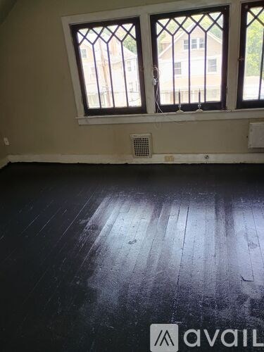 A room with a window and a wooden floor.