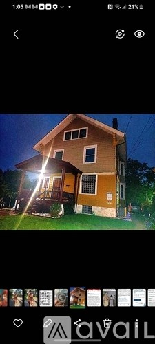 A house with a yellow exterior and a brown roof is illuminated by a bright light.