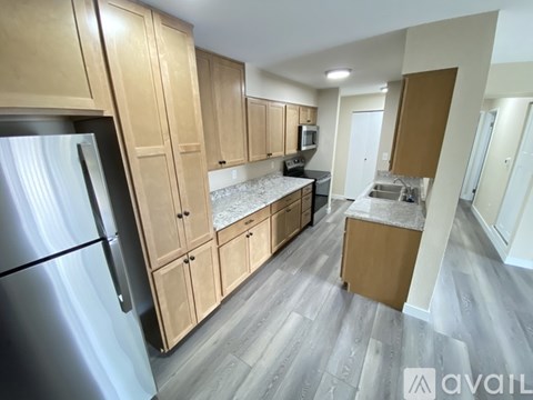 A kitchen with wooden cabinets and a stainless steel refrigerator.