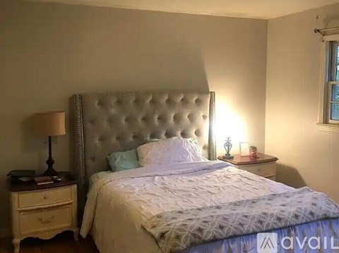 A bedroom with a white bed and a lamp on a nightstand.