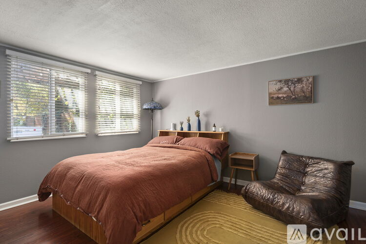 A bedroom with a bed, a chair, and a painting on the wall.