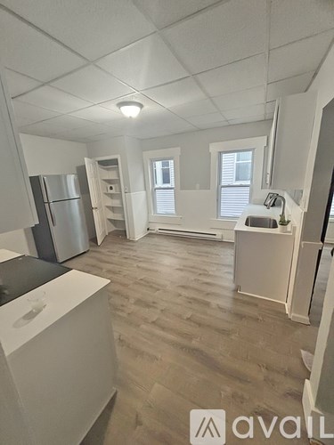 A kitchen with a refrigerator, sink, and cabinets.