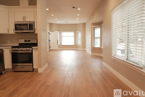 A spacious kitchen with wooden floors and a stove top oven.
