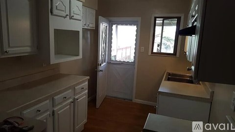 A kitchen with white cabinets and a window.