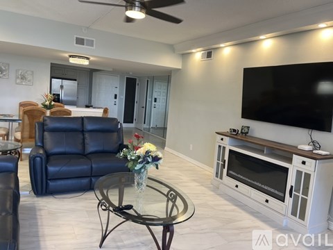 A living room with a black leather chair and a glass coffee table.