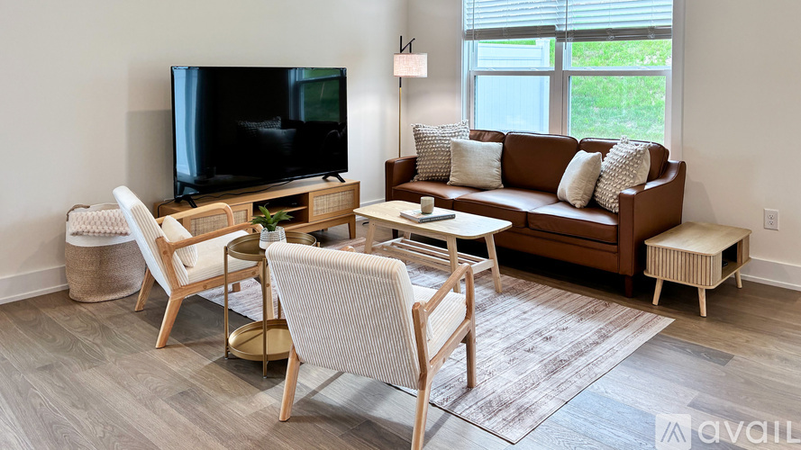 A living room with a brown couch, a white chair, and a television.
