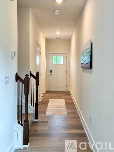 A hallway with a wooden floor and a white door.
