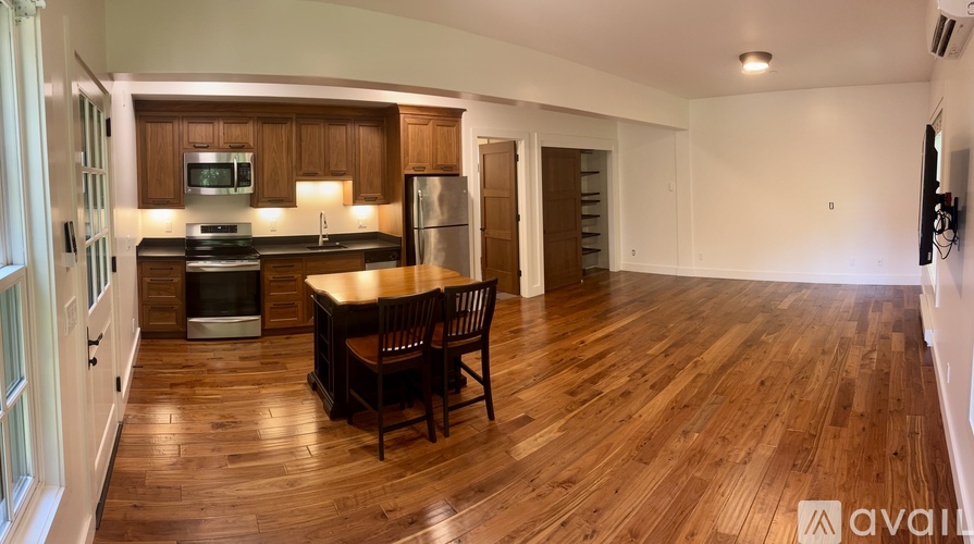 A kitchen with wooden floors and a dining table with chairs.