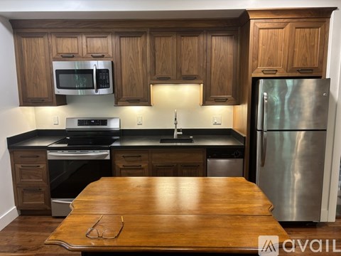 A kitchen with wooden cabinets and a stainless steel refrigerator.