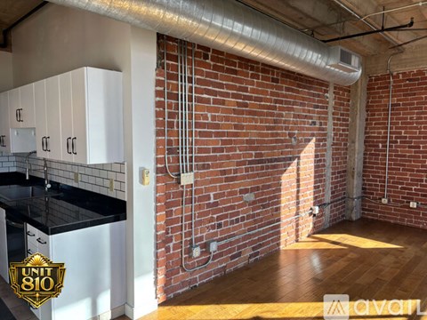 A kitchen area with white cabinets and a brick wall.