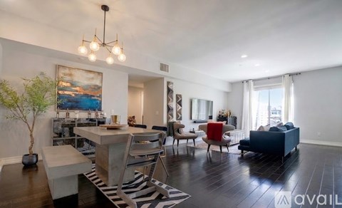 A living room with a dining table and chairs, a couch, and a painting on the wall.