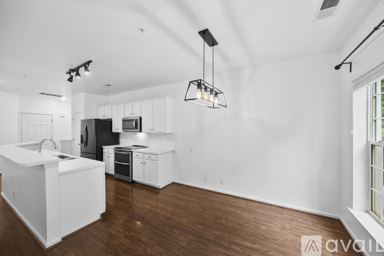 A modern kitchen with white cabinets and a wooden floor.