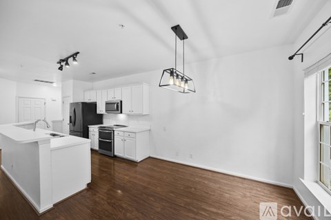 A modern kitchen with white cabinets and a wooden floor.